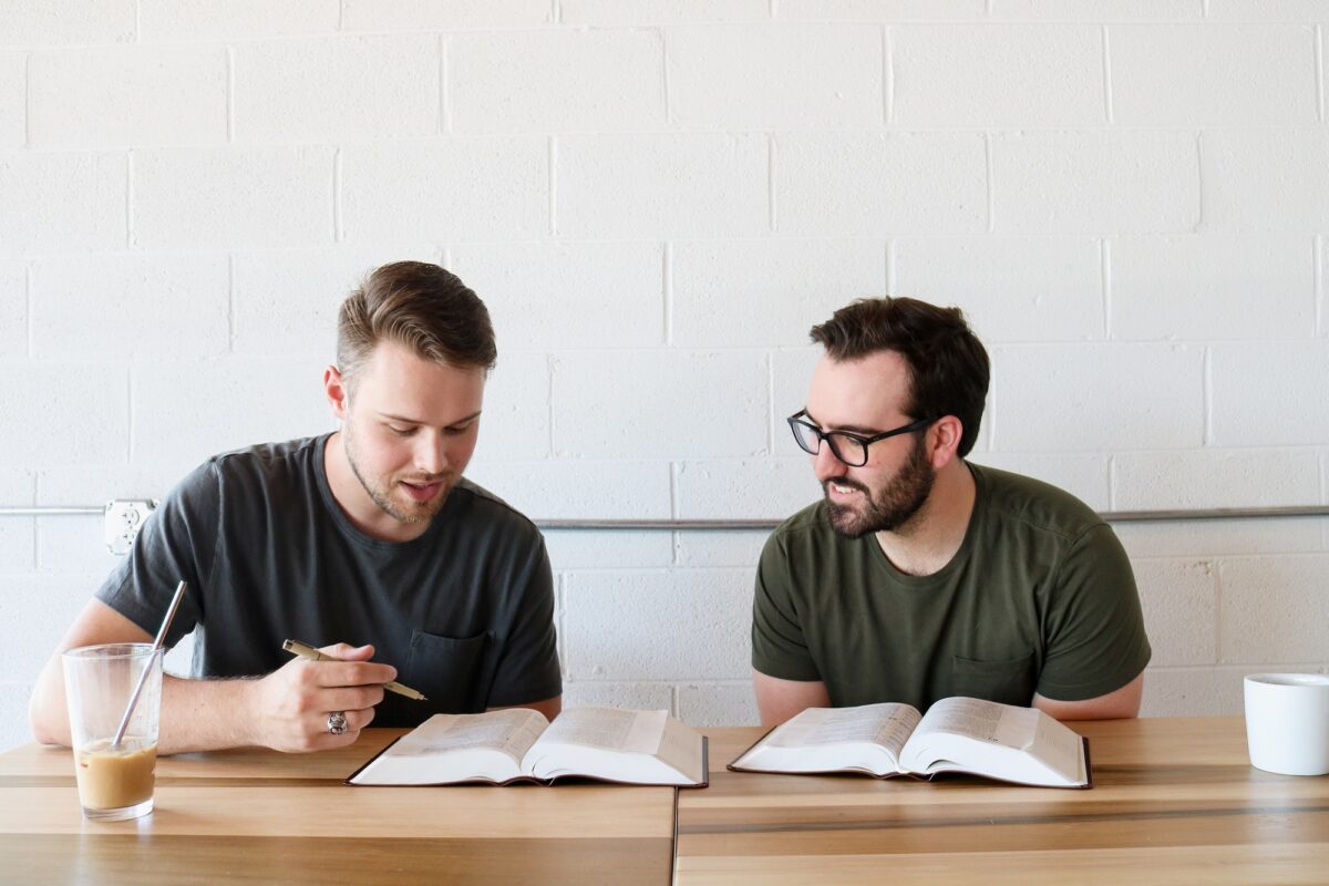 Two men sitting at a table with their Bibles open in a Bible study discussion